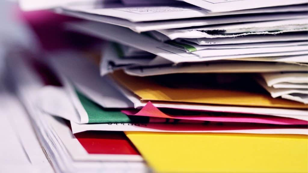 Stack of disorganized business documents and files for tax preparation.